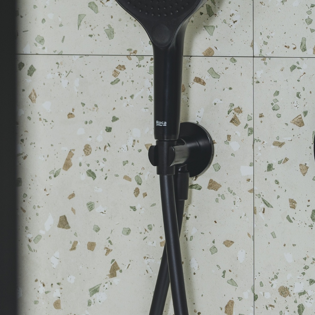 Lifestyle image of the Roca Aqua Matt Black Wall Bracket & Outlet mounted on a tiled bathroom wall